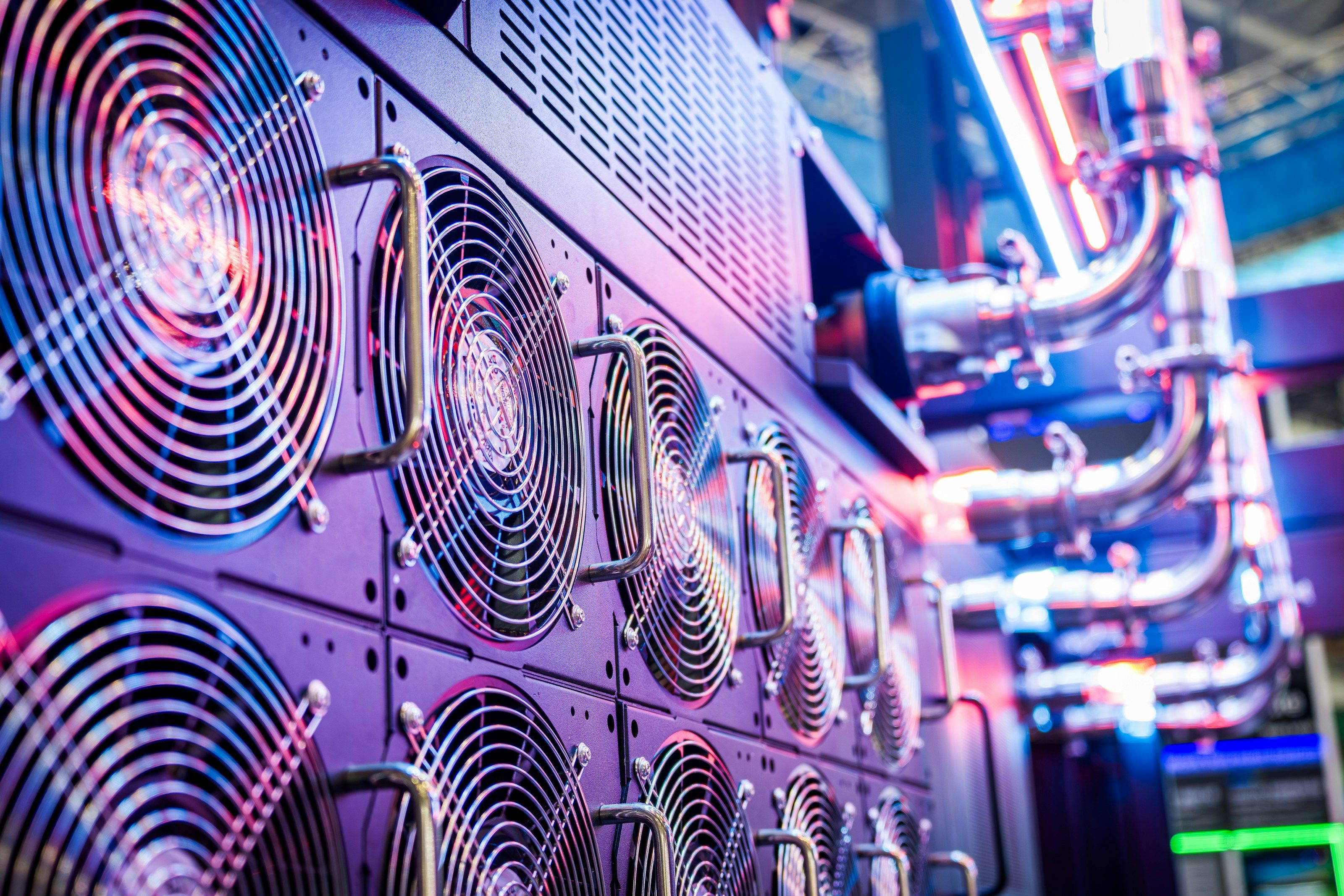 A row of cooling fans on rack-mounted hardware, lit in pink and blue