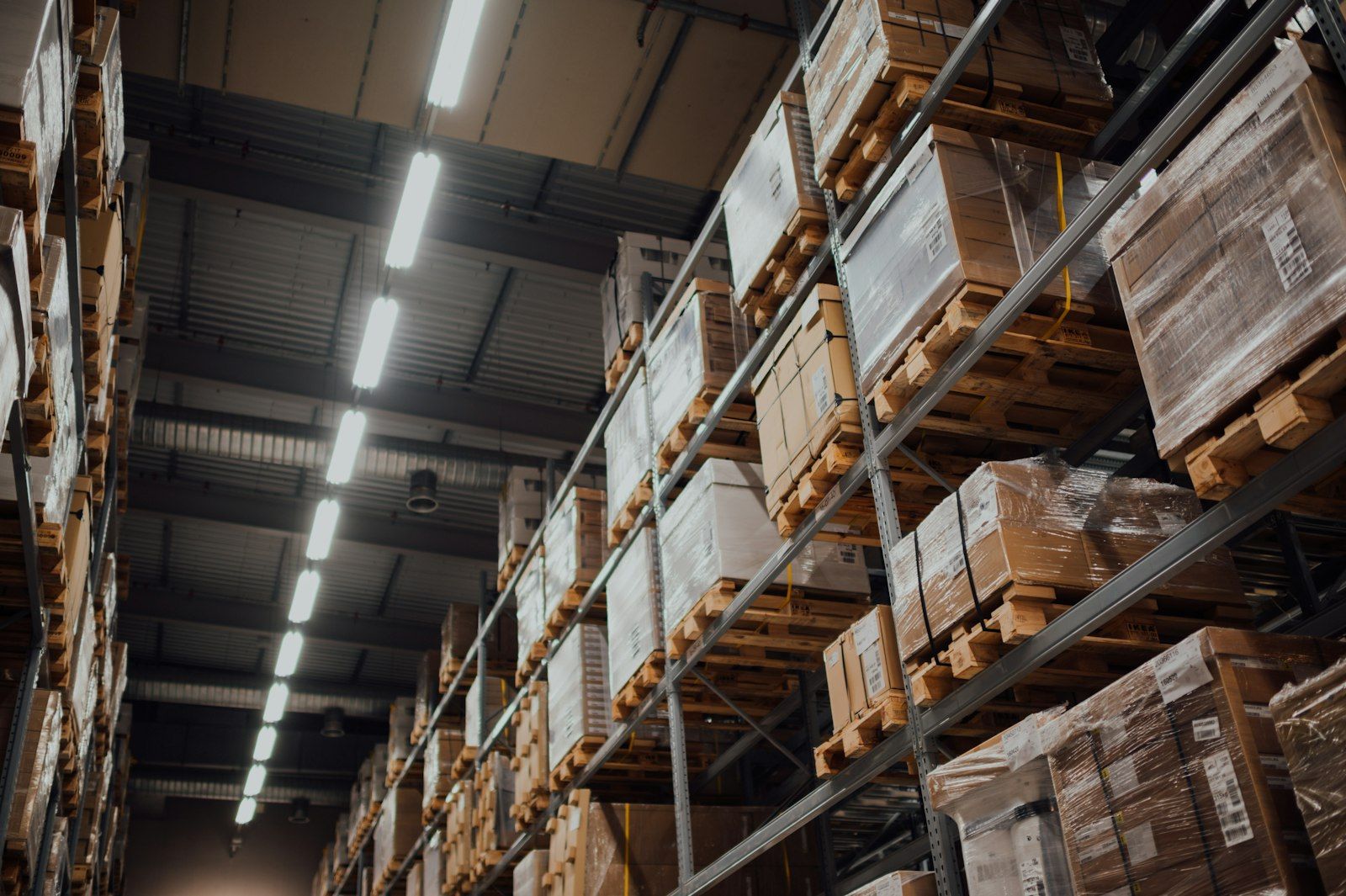 Plain cardboard cartons shrink-wrapped on wooden pallets in warehouse racking