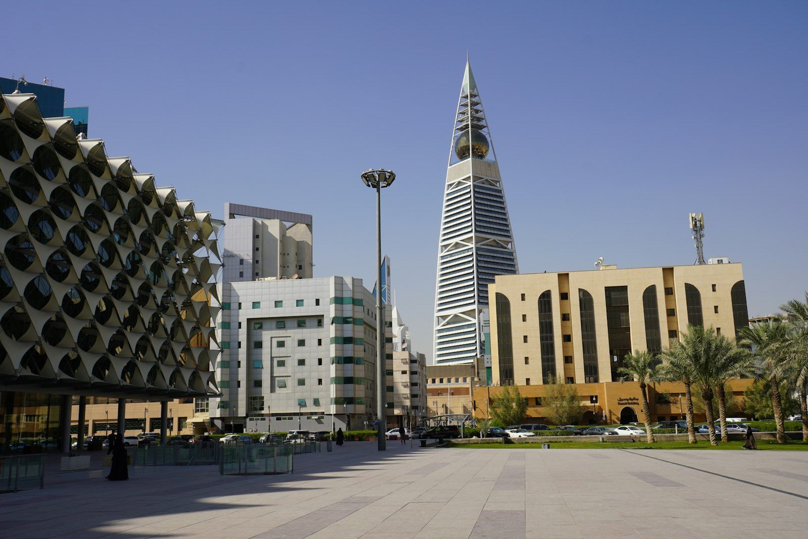High-rise towers and palm trees above an open plaza in a city under clear skies