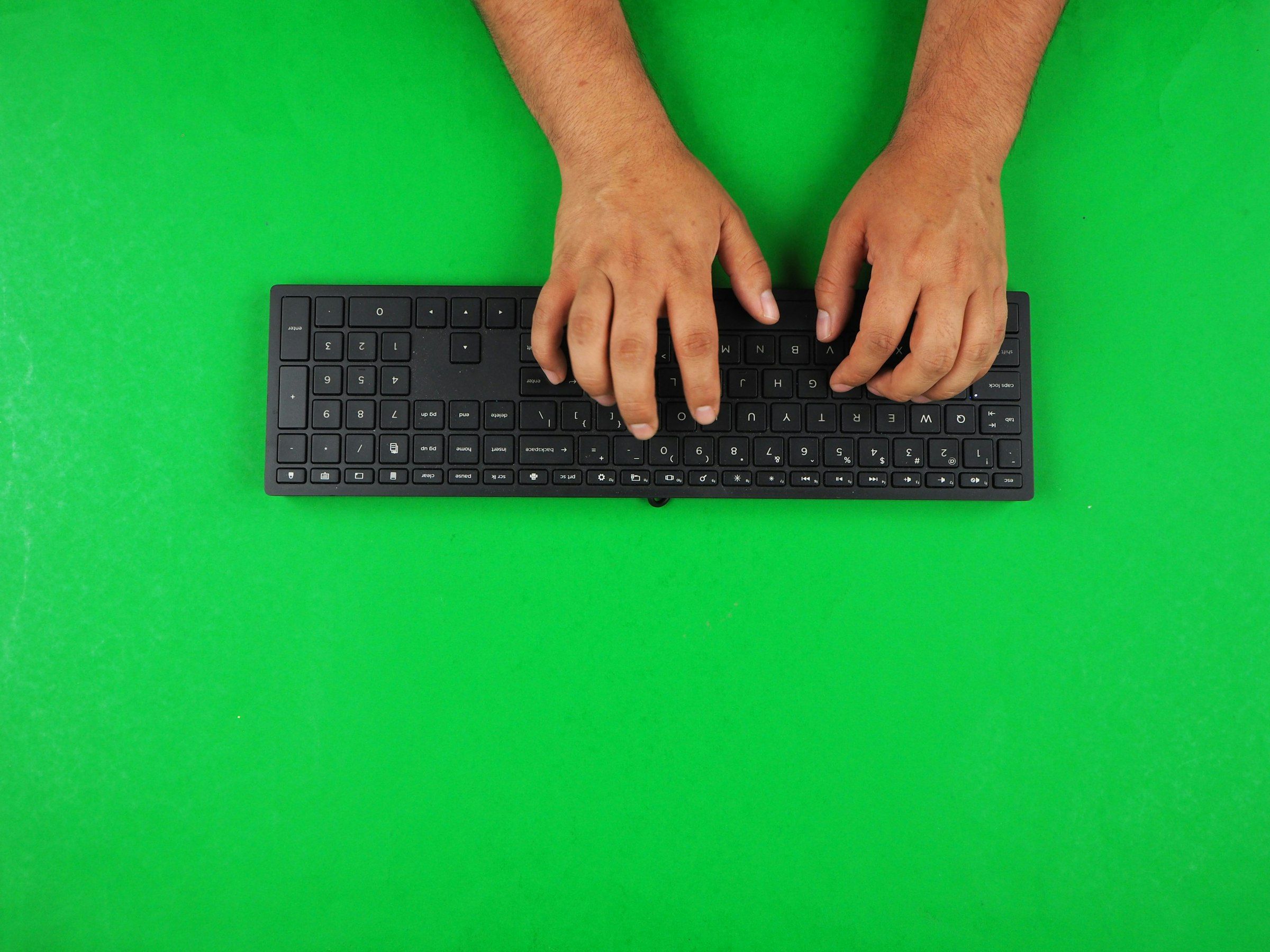 A pair of hands typing on a black keyboard, photographed from directly overhead
